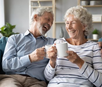 Overjoyed,Mature,Family,Couple,Sitting,On,Couch,,Enjoying,Pleasant,Conversation,